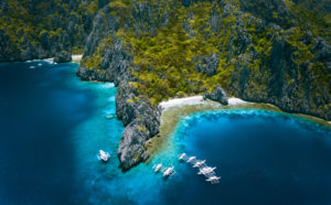 El Nido, Palawan, Philippines. Aerial view of Miniloc Island with diving boats above coral reef surrounded by karst limestone rugged mountain cliffs. El Nido, Palawan, Philippines. Aerial view of Miniloc Island with diving boats above coral reef surrounded by karst limestone rugged mountain cliffs.